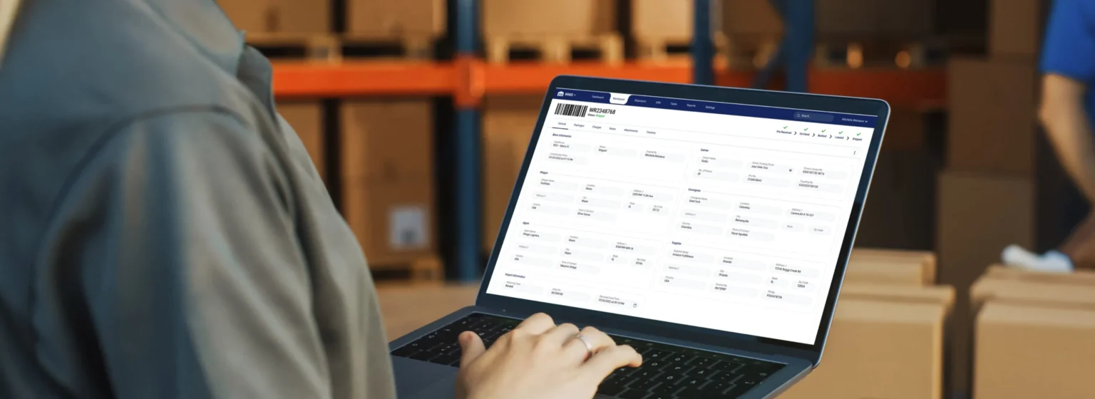 Warehouse manager using a Warehouse Management System on a laptop.